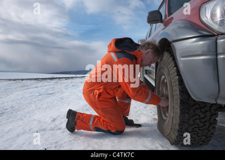 El hombre dejando salir el aire del neumático, Glaciar Myrdalsjokull Jeep, Islandia