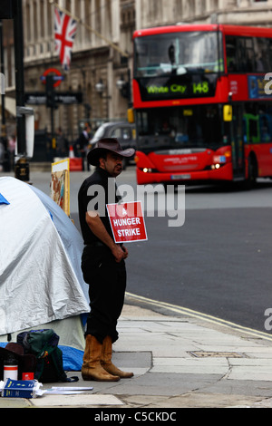Un manifestante que lleva un cartel 'Una huelga de hambre' en la Campaña por la Paz de Parliament Square / Brian Haw Peace Camp, autobús rojo en el fondo, Westminster, Londres Foto de stock