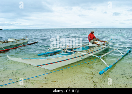 Un pescador del ajetreado con redes de pesca en sus canoas de batanga, Malapascua.