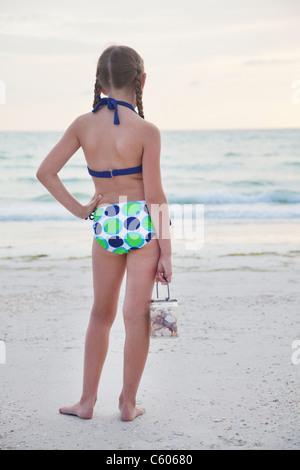 Ee.Uu., Florida, St. Pete Beach, vista trasera de chica (8-9) que sujetan el tarro de conchas en la playa