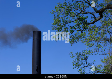 Fumar chimenea contra el cielo azul Foto de stock
