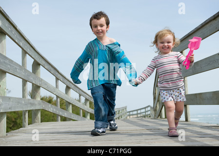 Hermanos jóvenes caminando de la mano en el Boardwalk