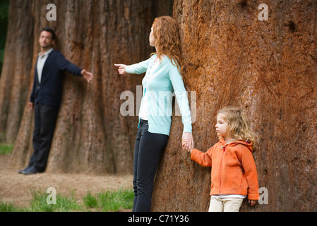 Los padres inclinada contra árboles separados, llegando el uno para el otro Foto de stock