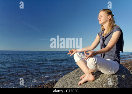 Mujer meditando en la playa Foto de stock