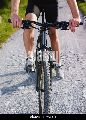 Actividad deportiva: adulto joven ciclista montando bicicleta de montaña en el campo. De forma vertical, vista recortada, bajo la sección