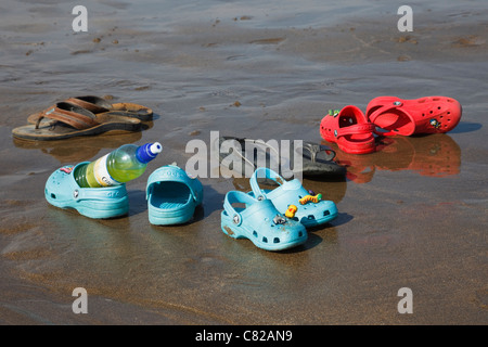 Botella para beber, sandalias y zapatos Crocs plástico abandonado en una  playa de arena húmeda por una familia con 3 niños en verano. Inglaterra,  Reino Unido (Gran Bretaña Fotografía de stock - Alamy