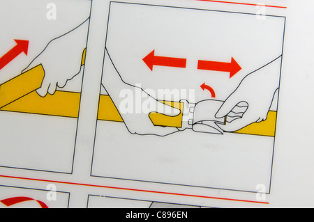 Primer plano de una tarjeta de seguridad aérea que muestra cómo abrir los cinturones de seguridad Foto de stock