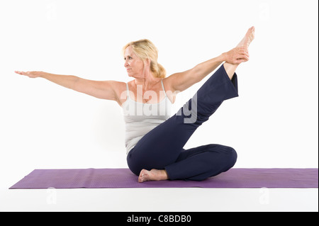 Mujer de mediana edad Hacer yoga sobre fondo blanco.