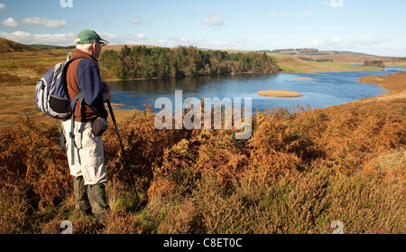 Walker en el pintoresco paisaje otoñal buscando Loch Mannoch galloway Escocia UK Foto de stock