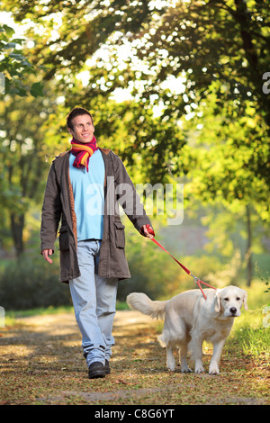 Un muchacho y su perro Labrador retriever a caminar en el parque en otoño