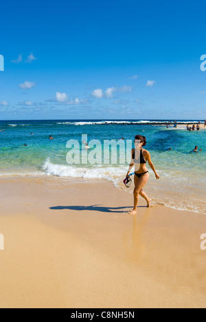 Mujer saliendo del océano con snorkel y máscara en un día soleado en la playa Poipu Beach, costa sur de Kauai, Hawaii Foto de stock