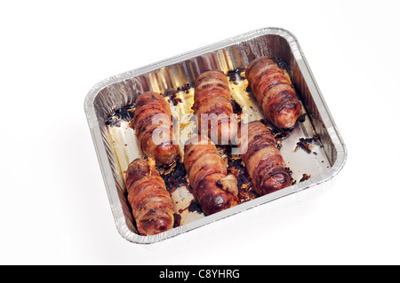 Los cerdos en una manta o piggies en mantas, salchichas envueltas en tocino, pan tostado sobre fondo blanco del recorte. Foto de stock