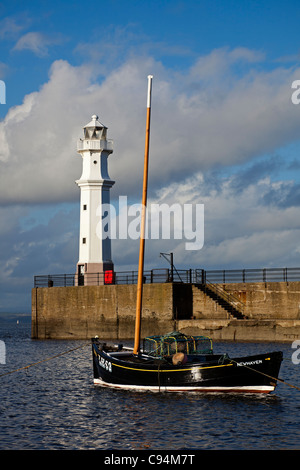 Barco de pesca con faro en fondo en Newhaven, Puerto de Leith, Edimburgo, Escocia, Reino Unido, Europa Foto de stock