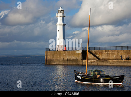 Barco de pesca con faro en fondo en Newhaven, Puerto de Leith, Edimburgo, Escocia, Reino Unido Europa Foto de stock