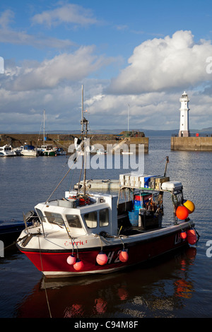 Barco de pesca con faro en fondo en Newhaven, Puerto de Leith, Edimburgo, Escocia, Reino Unido Europa Foto de stock
