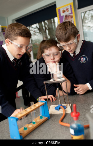 Un grupo de tres chicos de escuela secundaria los niños en una clase de ciencias química de laboratorio práctico, Gales, Reino Unido Foto de stock