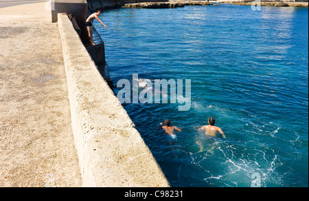 Los adolescentes nadando a lo largo del 'Malecon' en La Habana, Cuba. Foto de stock