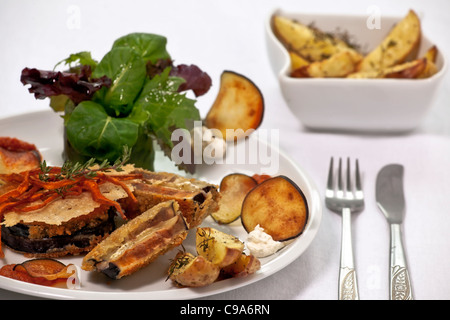 Berenjena Cordon Bleu rellenas con queso suizo y pesto rojo, servido con patatas de tomillo Foto de stock