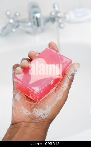 Mano de adolescente que sujetan la barra de jabón con forma de corazón, Ciudad del Cabo, en la provincia de Western Cape, Sudáfrica