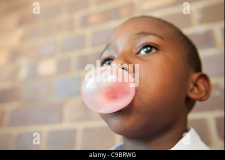 Muchacho soplando burbujas con la goma de mascar, Johannesburgo, en la provincia de Gauteng, Sudáfrica Foto de stock