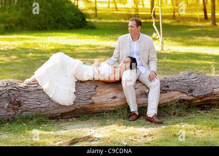 Mujer acostada sobre marido pierna en un parque tronco justo casado