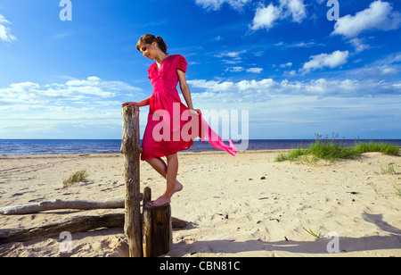 La joven con vestido rojo en la playa.