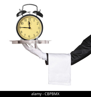 Una mano sujetando una bandeja de plata con un reloj despertador retro sobre ella Foto de stock