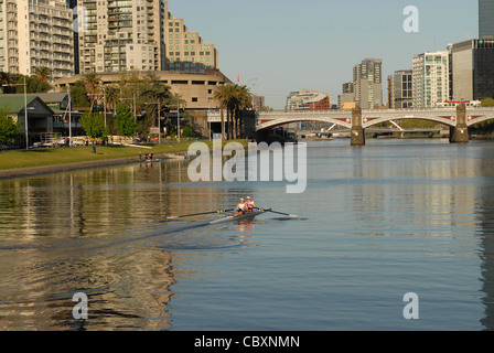 Temprano en la mañana de remo en el río Yarra, en el centro de Melbourne, con el Southbank (izq.) y el CDB (r.) en Melbourne, Victoria, Australia