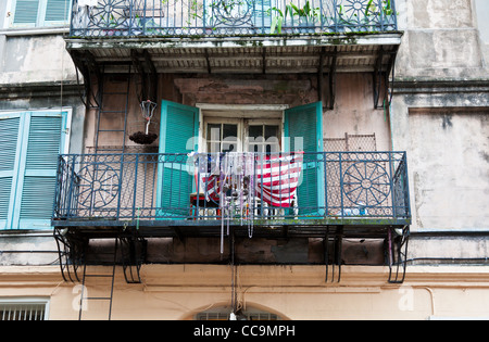 Mardi Gras beads y una bandera Americana colgando en una barandilla balcón de hierro forjado en el Barrio Francés de Nueva Orleans, Luisiana Foto de stock