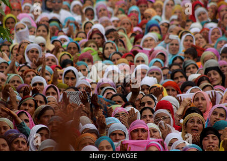 La mujer musulmana de Cachemira devotos elevan sus manos para orar como jefe sacerdote muestra una reliquia del Islam, el profeta Mahoma en el santuario de Hazrat Bal viernes siguiente de Mehraj-u-Alam, creído para marcar la ascensión del profeta Mahoma al cielo, en Srinagar, la summercapital indio de Cachemira en 8/7 Foto de stock