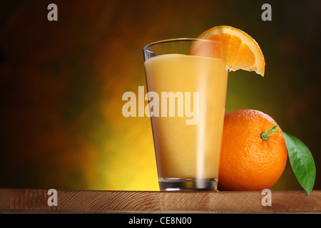 Las naranjas y un vaso de jugo en una mesa de madera. Foto de stock