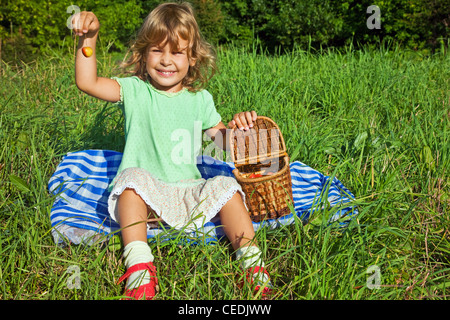 Pretty Little Girl se mantiene en la mano cerezas dulces en el jardín Foto de stock