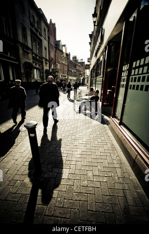 Las sombras de la gente caminando por las calles del casco. Foto de stock