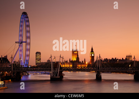 La vista a lo largo del río Támesis, el London Eye (Rueda del Milenio), las Casas del Parlamento y el Big Ben al atardecer, Londres, Reino Unido.