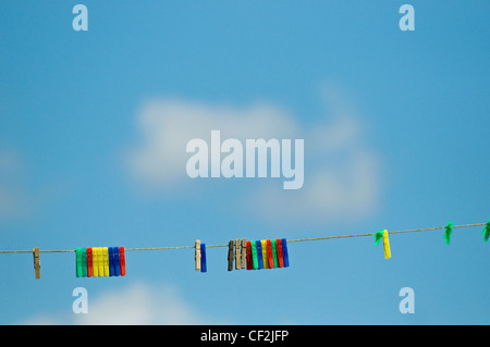 Colorida ropa clavijas en una línea de lavado contra un cielo azul. Foto de stock
