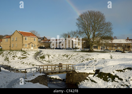 Un arco iris en vistas de Hutton Le Hole Village en invierno. Foto de stock