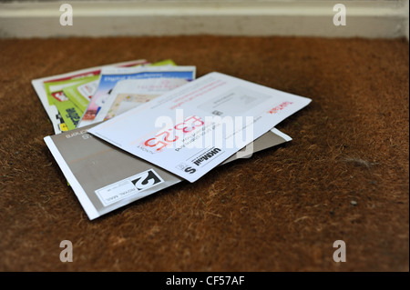 El correo basura en una casa privada en la alfombrilla de la puerta después de ser entregado por el cartero UK Foto de stock