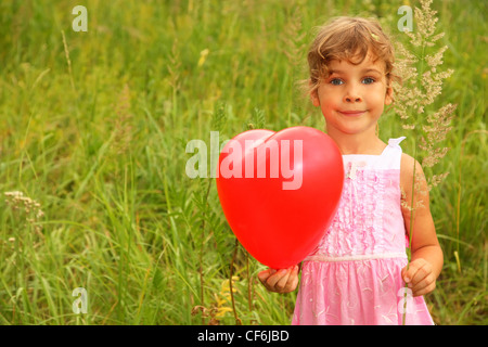Hermosa niña vestido rosado celebración globo rojo. Chica en la naturaleza