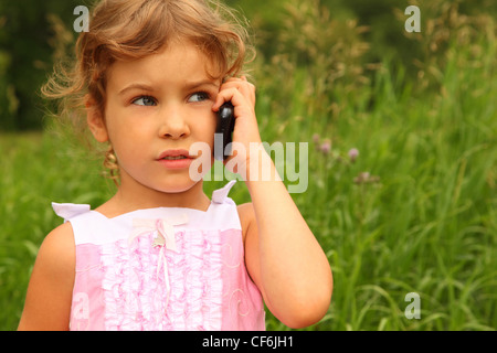 Hermosa niña vestido rosado hablando por teléfono celular al aire libre
