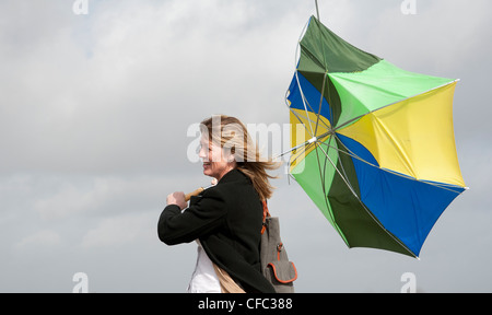 Mujer sosteniendo en su paraguas que ha fundido dentro fuera en un alto el viento Foto de stock