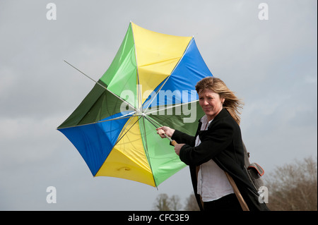 Mujer sosteniendo en su paraguas que ha fundido dentro fuera en un alto el viento Foto de stock