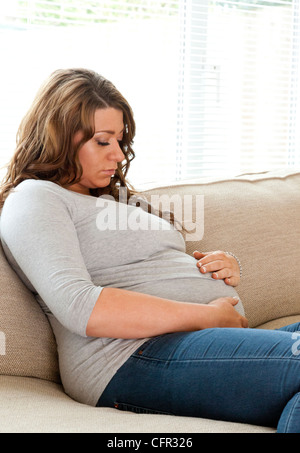 La mujer embarazada se sentó en el sofá Foto de stock