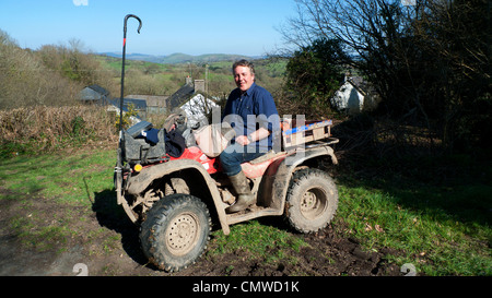 Un granjero galés en su quad en Llanwrda excepcionalmente cálido clima primaveral, Carmarthenshire, Gales del Sur, Kathy DEWITT Foto de stock