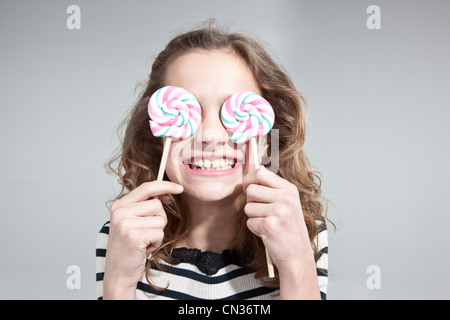 Chica, cubriéndose los ojos con lollipops Foto de stock
