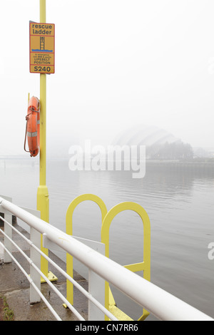 Escalera de rescate y Lifebelt junto al río Clyde en la niebla, Glasgow, Escocia, Reino Unido Foto de stock