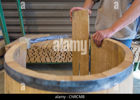 un barril de vino de madera y metal utilizado como una mesa en la cubierta  de madera del café. Un montón de barriles de madera a lo largo de la pared.  Terraza
