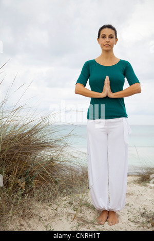 Mujer madura en posición de oración de yoga en la playa, Retrato