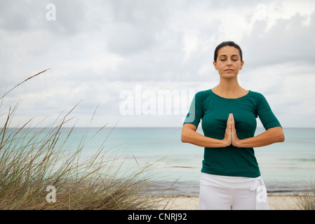 Mujer madura en posición de oración en la playa, Retrato