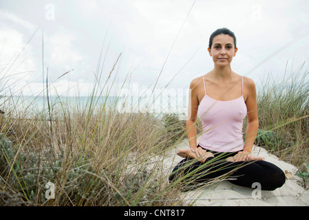 Mujer madura, sentado en la postura del loto, sobre la playa, Retrato