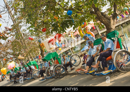 Vista horizontal del ciclo-rickshaws o cyclos y conductores esperando clientes en la antigua ciudad de Hoi An, Vietnam en un día soleado. Foto de stock